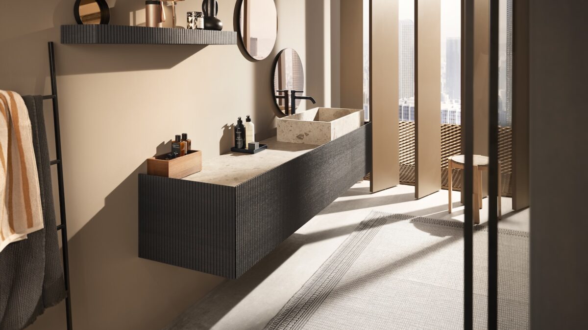 Modernes Badezimmer mit Waschtisch, hellen Steinoberflächen und dunklen Fronten, ausgestattet mit funktionalen Möbelbeschlägen von Blum.